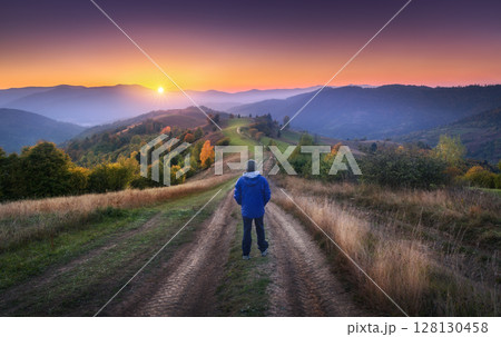 Man on the rural dirt road on the hill looking on mountain in fog 128130458