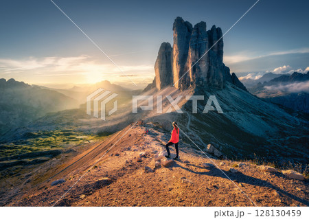 Hiker admiring Tre Cime di Lavaredo at sunrise in the Dolomites 128130459