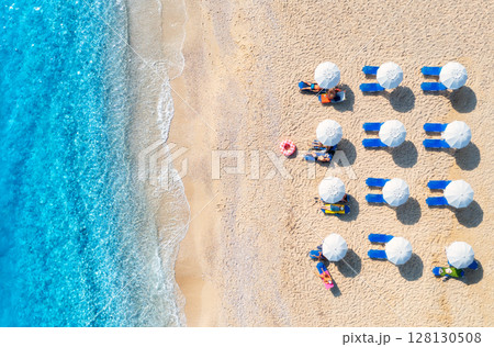 Aerial view of sunbeds under umbrellas on sandy beach Aerial view of sunbeds under umbrellas on sandy beach 128130508