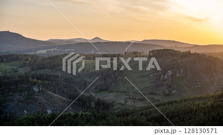 A stunning view from Popov Cliffs reveals the Lusatian Mountains bathed in the warm glow of sunset. Layers of hills and rocky formations create a dramatic landscape in Czechia, near Germany. 128130571