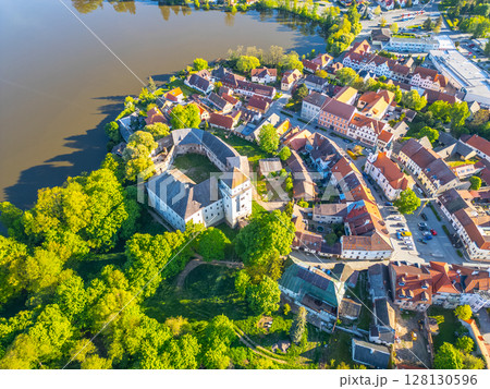 Overlooking the charming town of Rozmital pod Tremsinem, this view showcases the historic castle surrounded by lush greenery and serene waters, highlighting the beauty of Czechia. 128130596