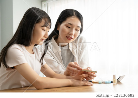 爪やすりで娘の爪先を整える母 128130692