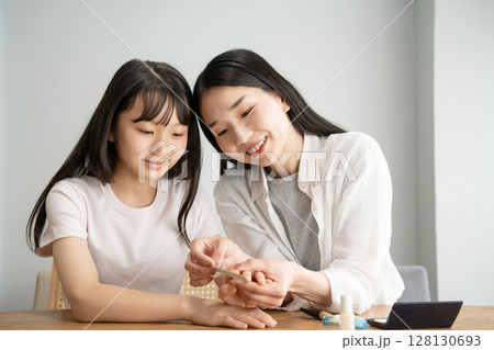 爪やすりで娘の爪先を整える母 爪やすりで娘の爪先を整える母 128130693