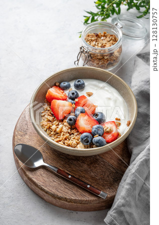 Natural yogurt with granola, blueberry and strawberry in a bowl on a light background Natural yogurt with granola, blueberry and strawberry in a bowl on a light background 128130757