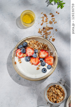 Natural greek yogurt with granola, blueberry and strawberry in a bowl on a light background Natural greek yogurt with granola, blueberry and strawberry in a bowl on a light background 128130759