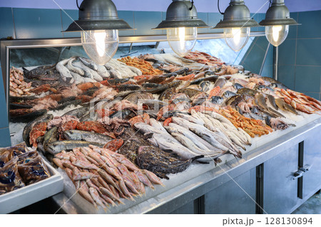Fish market bustling with activity where vendors display fresh catch on ice. Shiny fishes, shellfish, and crustaceans create colorful array, highlighting local seafood culture in Greece. 128130894