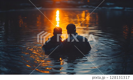 Silhouette of two people in calm water at sunset golden hour reflection 128131317