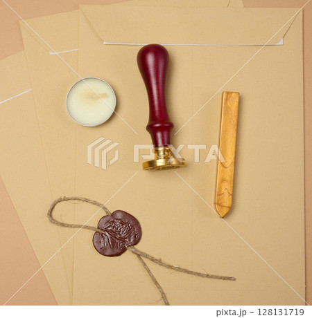 A wax seal kit including wax sticks, candles, stamp and sealed scroll placed on a neutral background 128131719