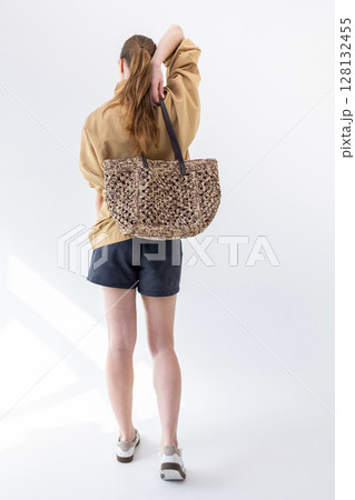 Elegant woman in beige windbreaker jacket and black shorts on light background. Fashionable female style. Studio photography. Vertical photo. Back view Elegant woman in beige windbreaker jacket and black shorts on light background. Fashionable female style. Studio photography. Vertical photo. Back view 128132455