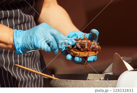 Chef Preparing a Gourmet Sandwich with Gloves in a Professional Kitchen 128132631