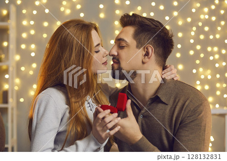 Happy young woman kissing her boyfriend after he gave her beautiful engagement ring 128132831