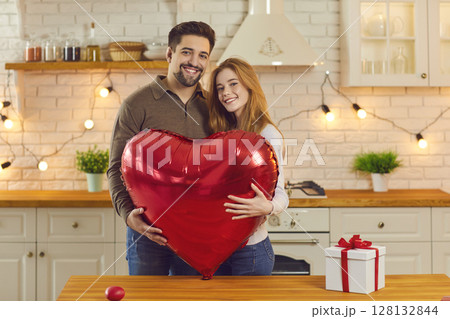 Happy couple holding huge balloon while celebrating Valentine's Day or having anniversary party Happy couple holding huge balloon while celebrating Valentine's Day or having anniversary party 128132844