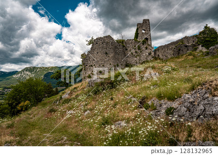 Ruins Of Grad Vipava In Slovenia: Ancient Stone Walls Covered In Ivy Standing On A Grassy Hilltop Under A Dramatic Cloud-Filled Sky In The Scenic Vipava Valley 128132965