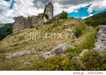 Ruins Of Grad Vipava In Slovenia: Ancient Stone Walls Covered In Ivy Standing On A Grassy Hilltop Under A Dramatic Cloud-Filled Sky In The Scenic Vipava Valley 128132981