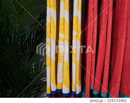 Row of towels with yellow and white stripes are hanging on a rack 128133962