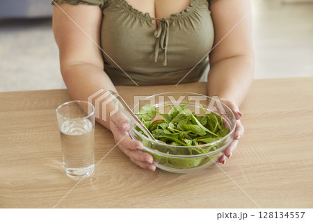 Healthy slimming vegetarian diet, salad in bowl, water glass, woman eating green vegetables Healthy slimming vegetarian diet, salad in bowl, water glass, woman eating green vegetables 128134557