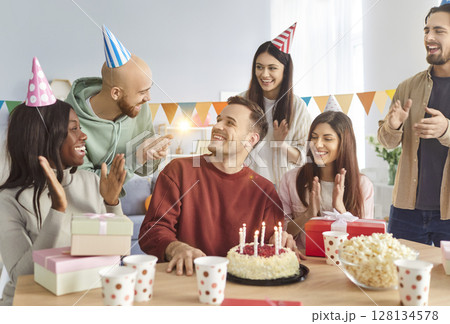 Happy diverse people group sitting at festive table with cake congratulating friend on his Birthday 128134578