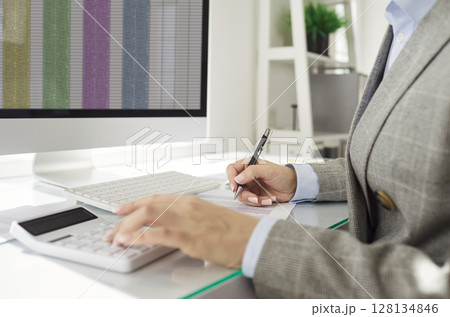 Financial accountant calculating expenses and reviewing financial spreadsheet on computer screen. 128134846