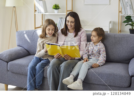 Family reading together, mother and small kids holding a book, enjoy warm and cozy shared activity Family reading together, mother and small kids holding a book, enjoy warm and cozy shared activity 128134849