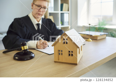 Judge woman in professional outfit black robe writing reviewing house jurisprudence documents Judge woman in professional outfit black robe writing reviewing house jurisprudence documents 128134852