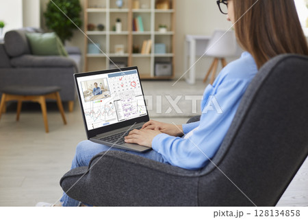 Woman sitting at home, working on laptop computer, using calendar and having video call 128134858