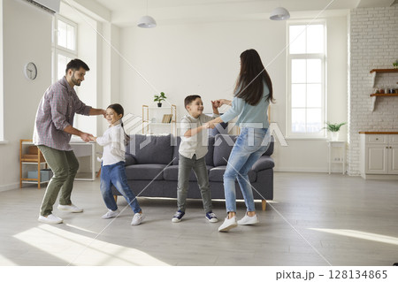 Happy parents and children dancing and having fun in their new house or apartment 128134865