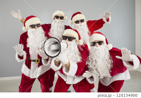 Funny people in Santa Claus costumes shouting announcement in megaphone. Christmas sale concept. Funny people in Santa Claus costumes shouting announcement in megaphone. Christmas sale concept. 128134900