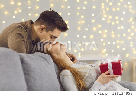 Side view of a loving husband kissing his young wife on the forehead after giving her a gift. Side view of a loving husband kissing his young wife on the forehead after giving her a gift. 128134953