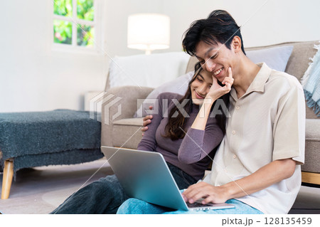 Happy Couple Relaxing at Home Using Laptop, Enjoying Modern Lifestyle in Cozy Living Room 128135459