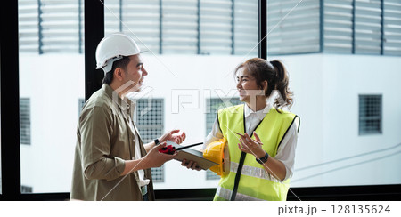 Professional Engineers Collaborating on Construction Project in Modern Office Setting with Safety Gear and Blueprints 128135624