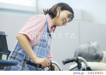 車椅子を押す介護士 車椅子を押す介護士 128135625