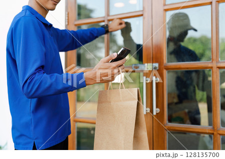 Delivery Service Worker Knocking on Door with Paper Bag and Smartphone, Modern Home Delivery Concept, Efficient and Fast Service for Online Shopping and Food Orders Delivery Service Worker Knocking on Door with Paper Bag and Smartphone, Modern Home Delivery Concept, Efficient and Fast Service for Online Shopping and Food Orders 128135700