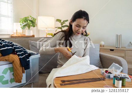 Woman Recycling Old Clothes at Home by Cutting Fabric for DIY Projects, Promoting Sustainable Living and Environmental Conservation Woman Recycling Old Clothes at Home by Cutting Fabric for DIY Projects, Promoting Sustainable Living and Environmental Conservation 128135817