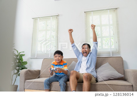 Excitement and Victory. Father and son celebrating while playing video games. 128136014