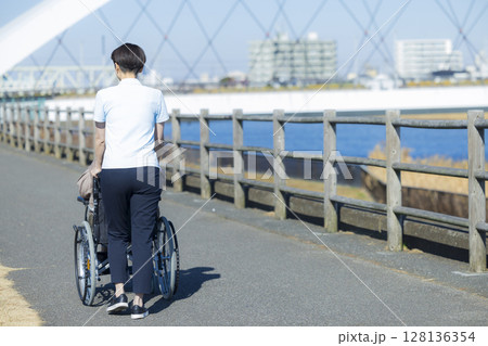車椅子に乗る女性性と介護士 車椅子に乗る女性性と介護士 128136354