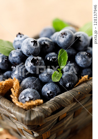 Ripe blueberries in wicker basket on wooden table. 128137946