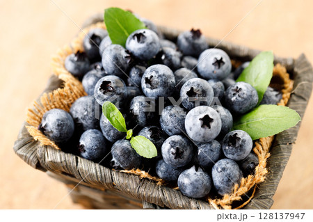 Ripe blueberries in wicker basket on wooden table. 128137947