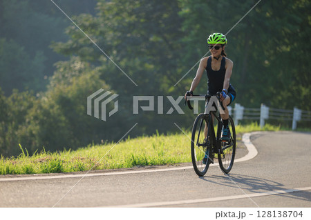 Fitness woman cyclist riding bike in summer park 128138704