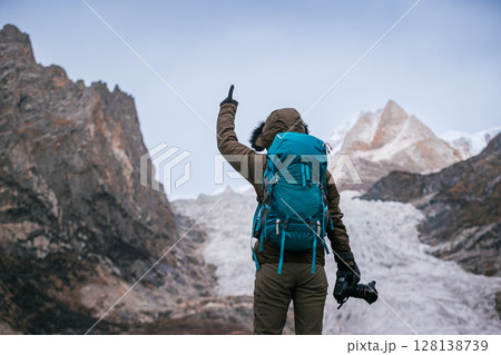 Hiking woman photographer shocked with the large hanging glacier in high altitude mountains Hiking woman photographer shocked with the large hanging glacier in high altitude mountains 128138739