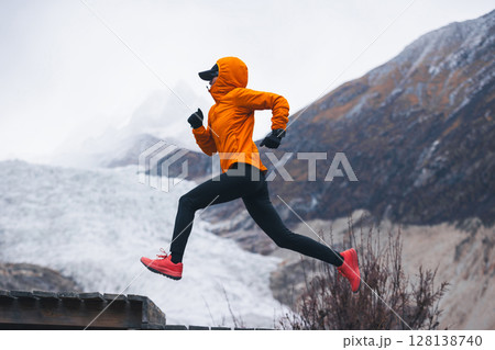Fitness woman trail runner running in grassland with snow capped mountains in the background Fitness woman trail runner running in grassland with snow capped mountains in the background 128138740