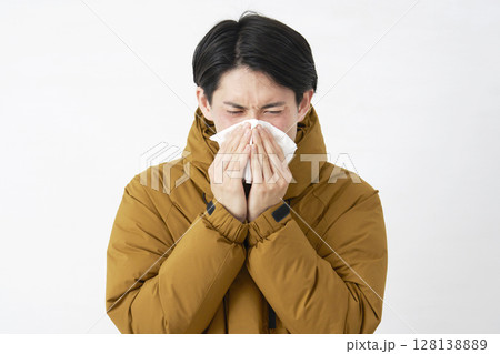 ダウンジャケットを着た男性　鼻をかむ　白背景 128138889