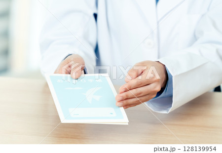 お薬手帳を渡す薬剤師の女性 お薬手帳を渡す薬剤師の女性 128139954