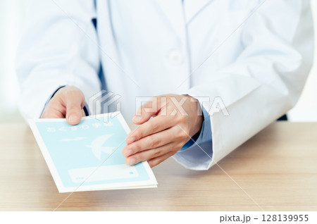 お薬手帳を渡す薬剤師の女性 128139955