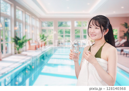 プールで水を飲んでクールダウンする水着姿の女性 プールで水を飲んでクールダウンする水着姿の女性 128140368