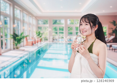 プールで水を飲んでクールダウンする水着姿の女性 プールで水を飲んでクールダウンする水着姿の女性 128140369