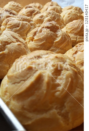 Light, airy cream puffs filled with luscious vanilla custard, dusted with powdered sugar. A delightful treat that melts in your mouth with each bite, perfect for any occasion. 128140417