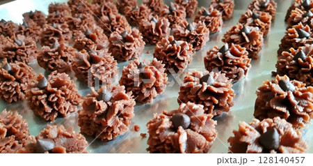 Delicate and crispy chocolate kue semprit with a rich cocoa flavor, beautifully shaped with a swirl pattern. A classic Indonesian cookie perfect for snacking or festive celebrations. 128140457