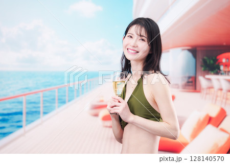 クルーズ船で水着を着てスパークリングワインを飲む若い女性 128140570
