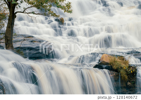 Beautiful waterfall with a lush green forest in the background. The water is flowing down the rocks and creating a beautiful scene. Sustainable waterfall in lush forest promoting water sustainability. 128140672