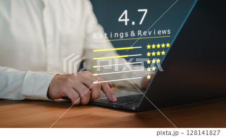 Customer types on a laptop with a digital overlay showing a 4.7 star rating and reviews. Business service concept of customer feedback, product evaluation, and user satisfaction in a digital context. 128141827